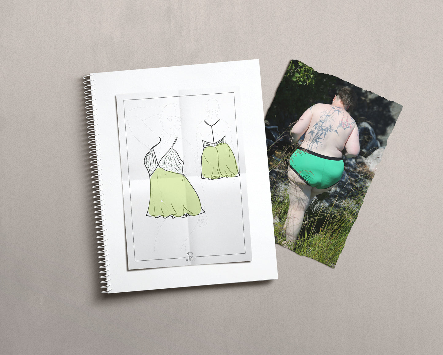 Drawing of a babydoll dress on a croquies, ontop of a notebook and a photo of a model wearing green knickers.