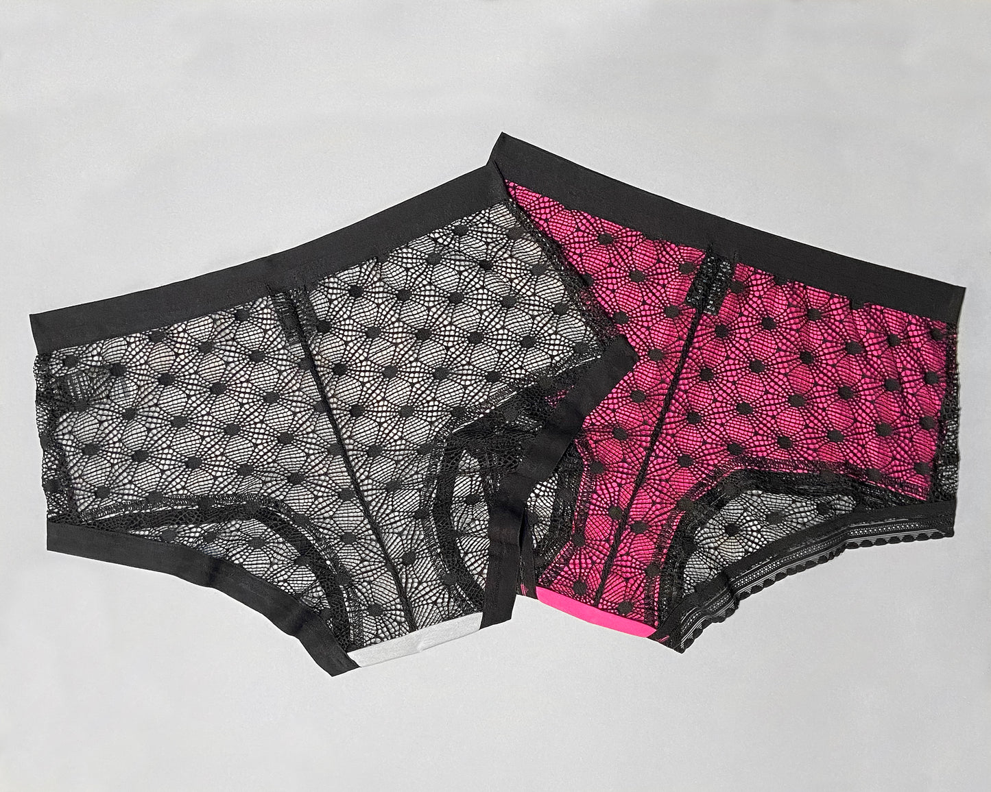 Back view of two samples of The Mix Hipster, in the pink and grey colourway. You can see the colour of the fabric through the sheer lace geometric pattern. The grey sample has the plain elastic in the legopening, the pink has the standard elastic in the legopening.