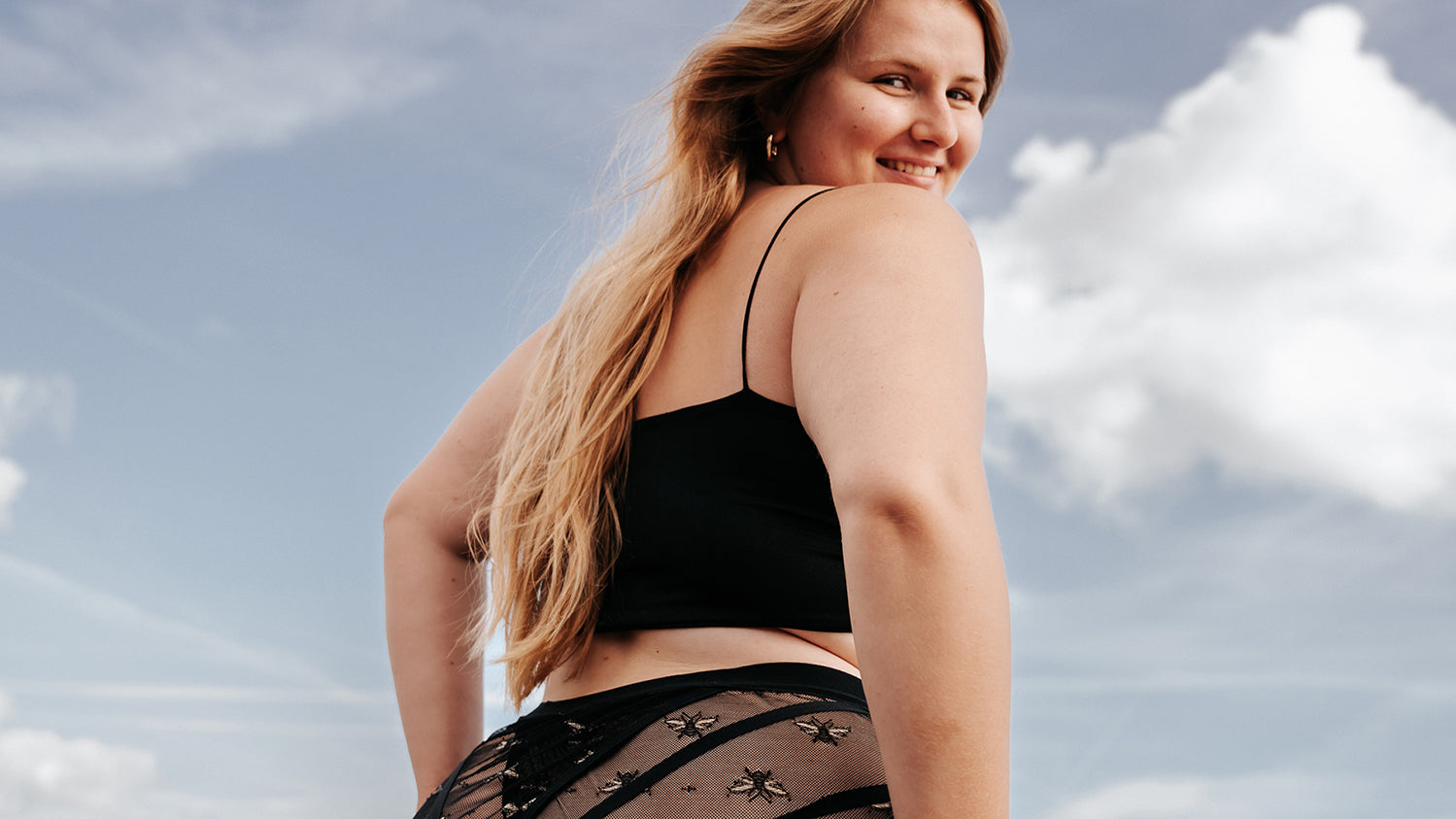 Smiling model wearing The Crossover Hipster, looking over her shoulder towards viewer.