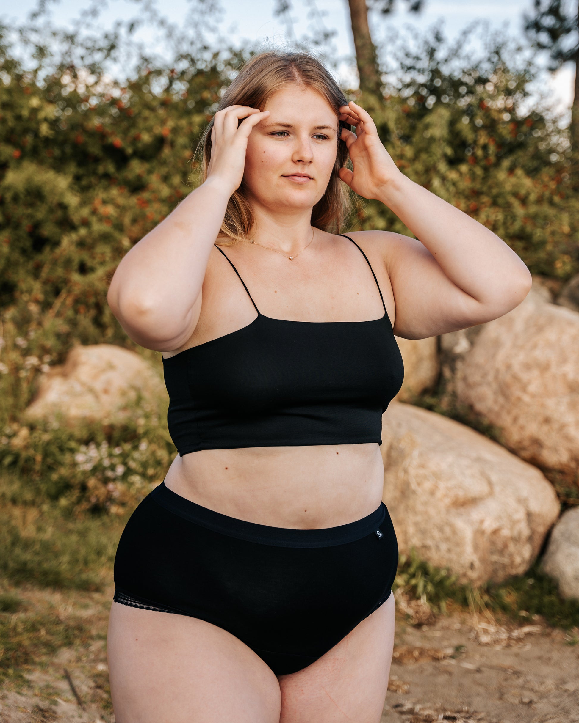 Front view of a model wearing The Bamboo Hipster, arms raised to arrange her long hair.