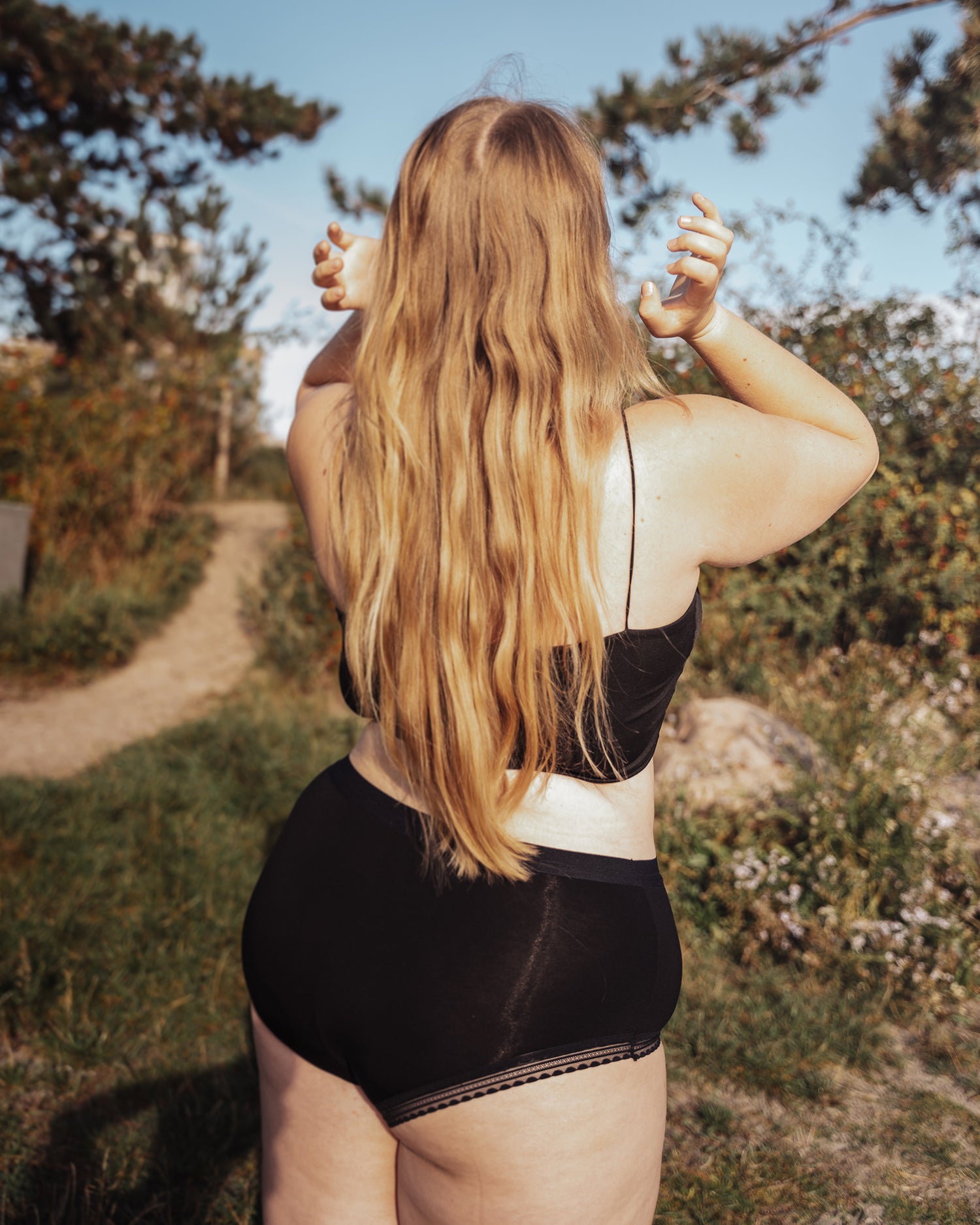 Model wearing The Bamboo Hipster, arranging her long hair with her back towards viewer.