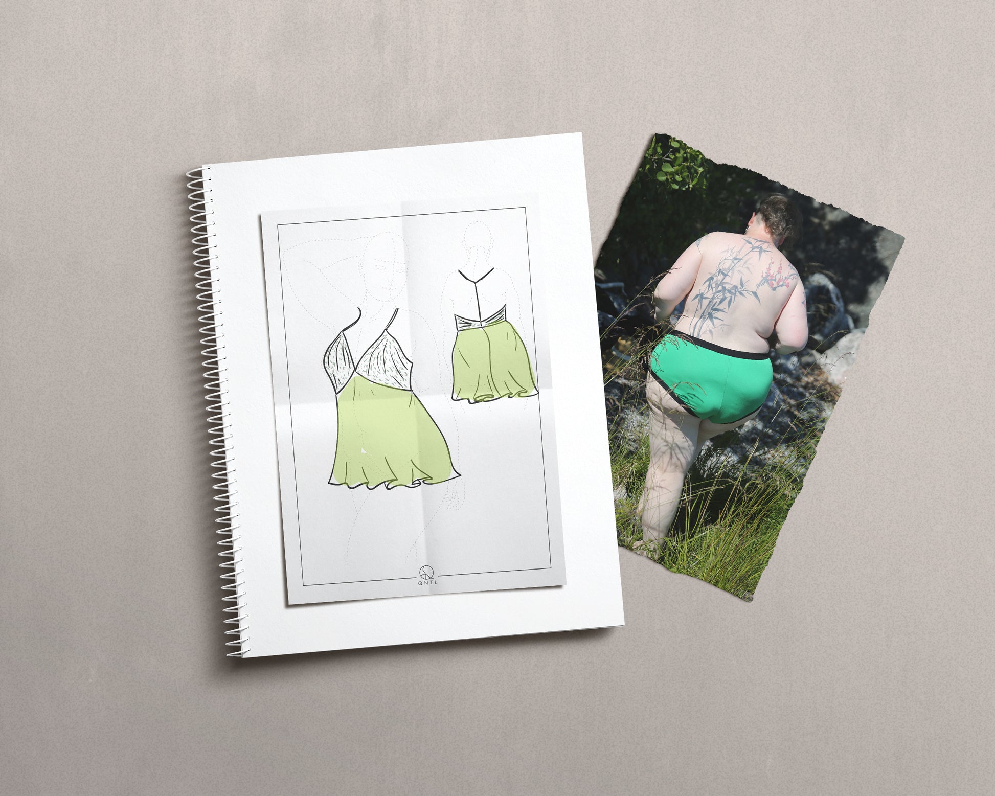 Drawing of a babydoll dress on a croquies, ontop of a notebook and a photo of a model wearing green knickers.